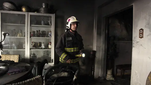 Un bombero inspecciona un piso incendiado en Zaragoza.
