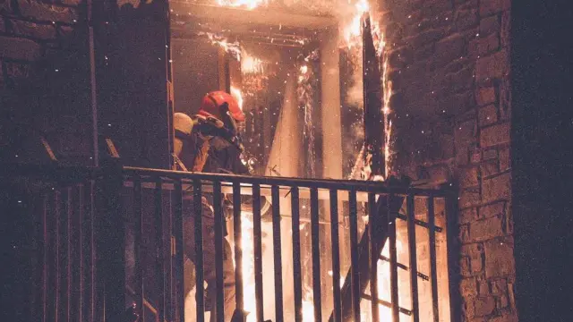 Un bombero, apagando el virulento incendio en el bloque de apartamentos de Benasque