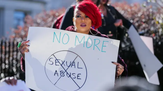 Una mujer sostiene un cartel que reza 'No más abusos sexuales' durante una protesta