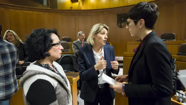 La coordinadora de la ponencia de la ley de renta básica, Pilimar Zamora, entre las diputadas de Podemos Amparo Bella y Violeta Barba, en el pleno.
