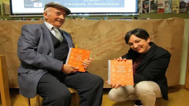 Ana Marcén y su abuelo, Miguel Murillo, posan con un ejemplar del libro. Heraldo.
