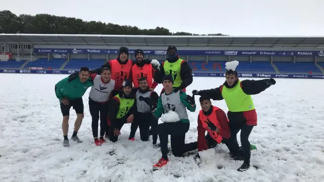 Varios jugadores del Huesca posando sobre un Alcoraz lleno de nieve tras acabar este miércoles el entrenamiento.