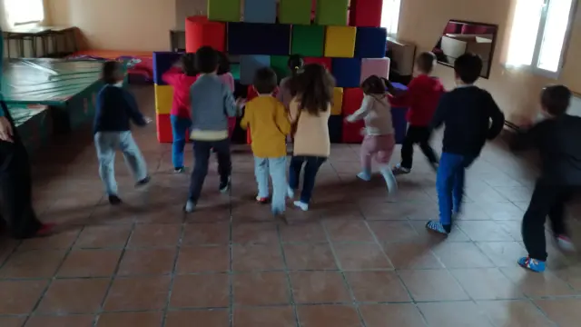 Un grupo de niños corre para derribar una muralla de bloques de goma espuma en el colegio de Villaspesa