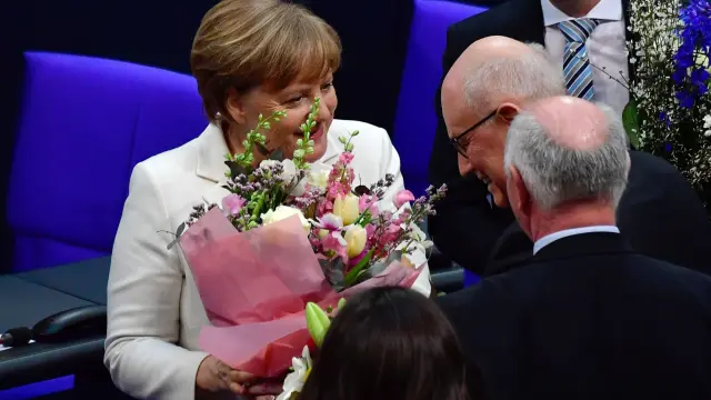 Merkel recibe un ramo de flores en el Parlamento.