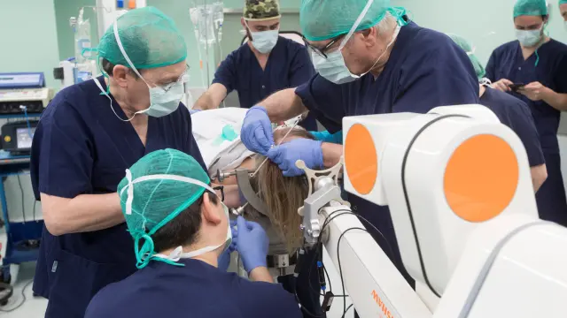 Neurocirujanos del centro médico Teknom de Barcelona junto al robot en la operación