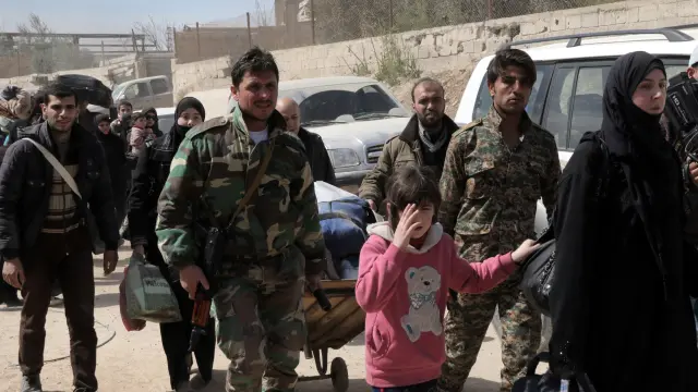 Soldados ayudan a que salgan sirios de Guta Oriental, este jueves, 15 de marzo.