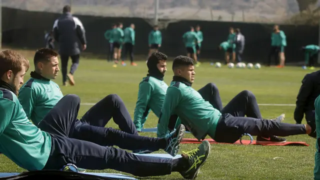 Algunos jugadores del Huesca realizan ejercicios de estiramiento durante un entrenamiento.