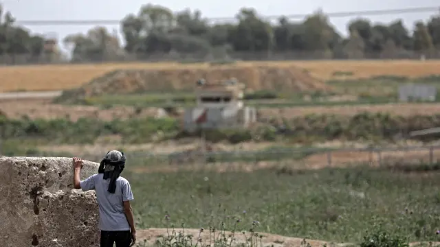Un niño palestino observa una torre militar israelí días antes de la protesta 'La Marcha del Retorno' en la frontera de Gaza