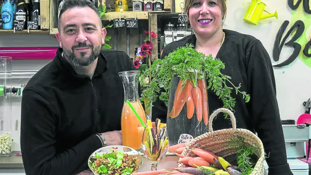 Óscar Lianes y Eva Muniesa, con distintas variedades de zanahorias y preparaciones como zumos, ensaladas y crudités en la frutería Muniesa.