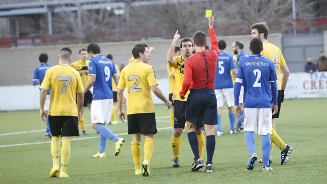 Un árbitro muestra una tarjeta amarilla durante un partido.