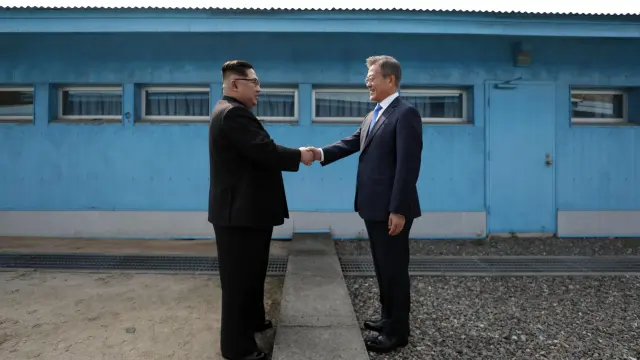 El presidente de Corea del Sur, Moon Jae -in, y el líder norcoreano Kim Jong-un se saludan en la línea de demarcación militar