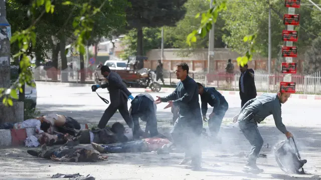 Un policía ayuda a periodistas víctimas de la segunda explosión en Kabul