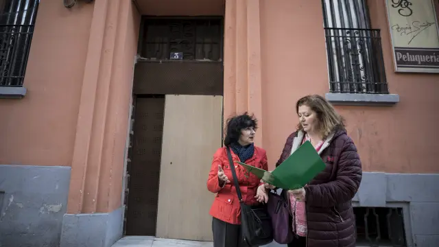 Tinita Fabián e Inmaculada Romeu ante la puerta 'antiokupas' de su edificio, en Gascón de Gotor.
