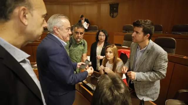 Nacho Escartín, a la derecha, habla con el socialista Javier Sada antes de comenzar el pleno de este jueves