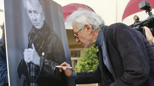 José Sacristán firma el cartel con su fotografía colocado por el Festival de Cine de Huesca en los Porches de Galicia.