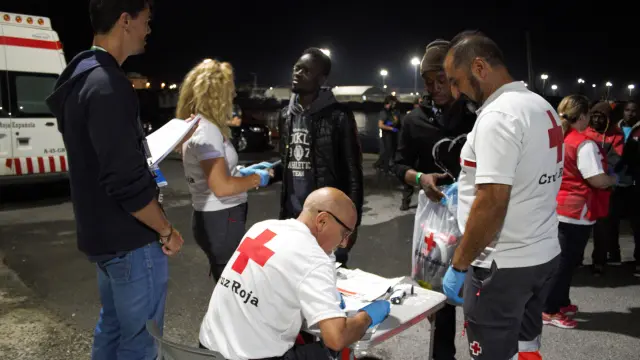 Miembros de Cruz Roja comprueban el estado de salud de varios inmigrantes rescatados de una patera.