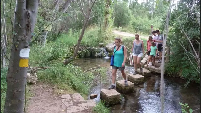 Un grupo de senderistas atraviesa un paso en la senda fluvial del río Alcalá, en la sierra de Gúdar.