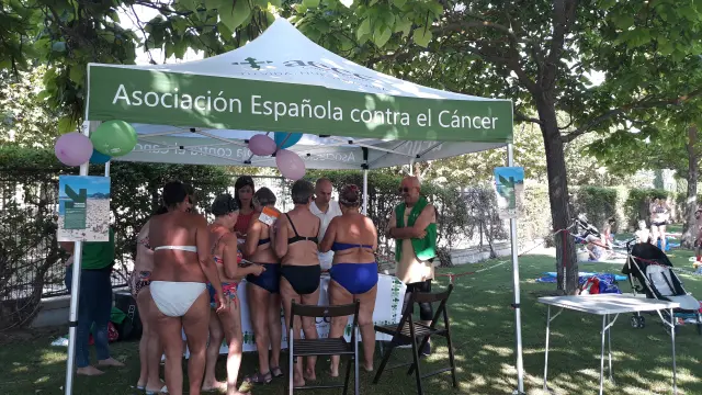 Bañistas en la carpa instalada por la AECC en las piscinas de la Ciudad Deportiva de Huesca.