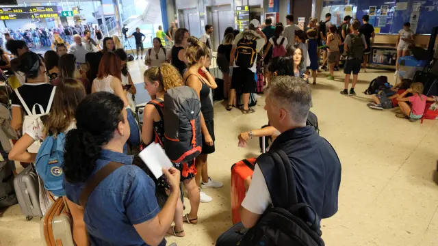 Pasajeros de Ryanair afectados por la huelga hacen cola en el mostrador de información del aeropuerto de Valencia.