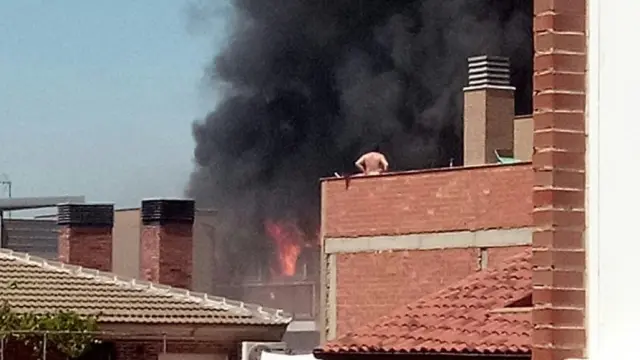 Un vecino contemplaba desde su terraza las llamas que salían de la vivienda incendiada.