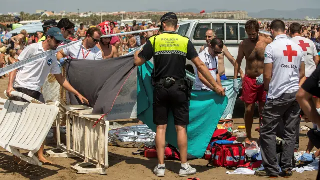 Miembros de la Cruz Roja, junto al cuerpo de un hombre que se ha ahogada en aguas de la playa de la Malvarrosa, en Valencia.