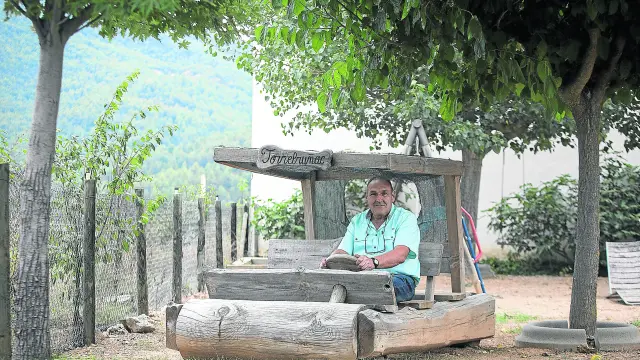 El fundador de Torrebruñac, José Román, en el troncomóvil a tamaño 'natural' que tiene en el jardín y que ha tallado él mismo.