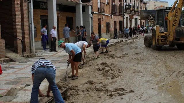 Varios vecinos limpian una calle cubierta de barro, tras la inundación que tuvo lugar ayer en la localidad toledana de Cebolla provocada por el desbordamiento del arroyo Sangüesa a su paso por el municipio