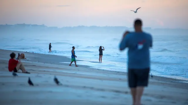 Varias personas toman fotografías al amanecer en una playa de Carolina del Norte.