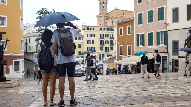Una pareja se protege de la lluvia bajo un paraguas en Mahón (Menorca)