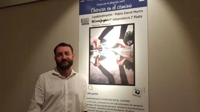 Pablo David, ante el cartel de su exposición 'Charcos en el camino'