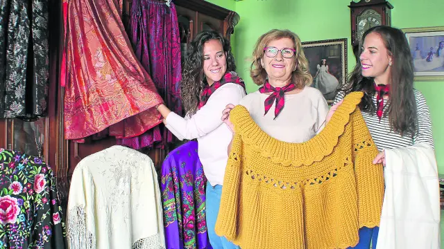 Delia y sus hijas, Elisa y Alba, en el salón de su casa con todas las prendas de ropa preparadas para lucirlas en la Ofrenda.