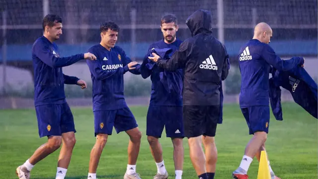 Álex Muñoz, Aguirre, Benito y Pombo recogen los chubasqueros al inicio del entrenamiento de este viernes, al arreciar con fuerza la lluvia que cayó todo el tiempo sobre la Ciudad Deportiva del Real Zaragoza.