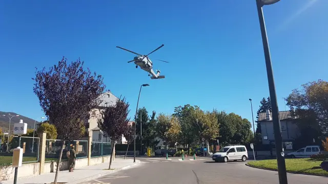 Un helicóptero aterrizando en la Escuela Militar de Jaca y pasando por encima del árbol cuya rama ha caído sobre dos mujeres