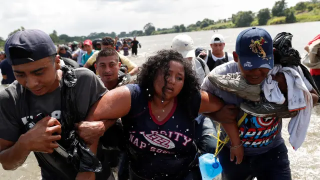 Una mujer es ayudada a cruzar el río Suchiate, en la frontera entre Guatemala y México