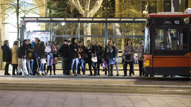Usuarios del bus urbano esperando bajo una marquesina en la plaza de Aragón.