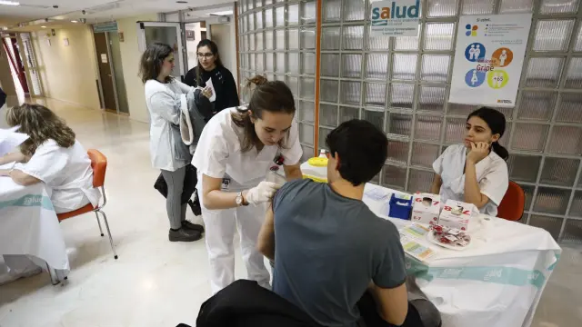 Dos alumnas de Enfermería de la Universidad de Zaragoza vacunan a uno de sus compañeros