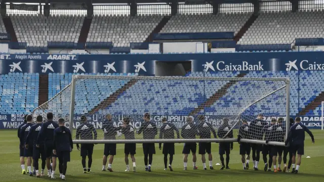 Los futbolistas del Real Zaragoza, en perfecta formación asidos a la portería móvil, durante el entrenamiento en La Romareda este domingo, previo al viaje a Tarragona.