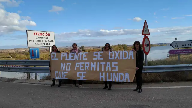 Reyes, Mari Carmen, María José y Tere, madres de alumnos, con una pancarta en el puente.