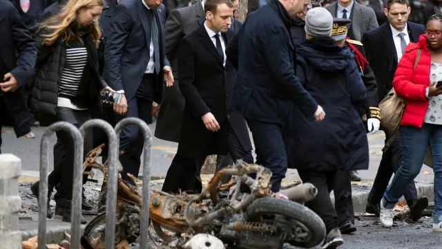 Macron pasa por delante de una motocicleta calcinada en los disturbios