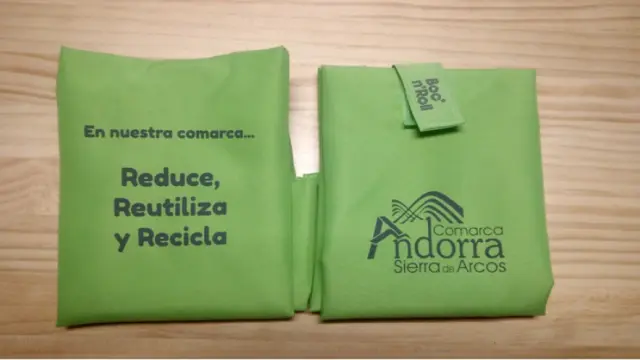 El portabocadillos es verde y lleva el logo de la comarca y un eslogan.