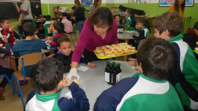 Pilar Pérez sirve pan con aceite a los escolares del colegio Sagrada Familia de Tarazona.