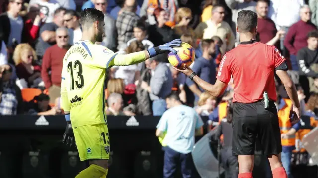 Roberto Santamaría le entrega la pelota a Gil Manzano durante el Valencia-SD Huesca.