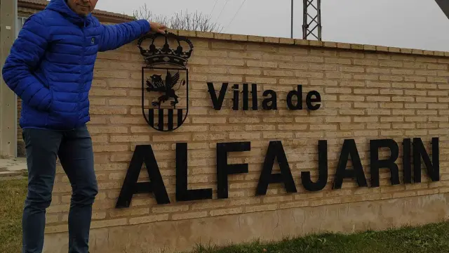 El alcalde de Alfajarín, junto a un letrero con la denominación de la localidad.