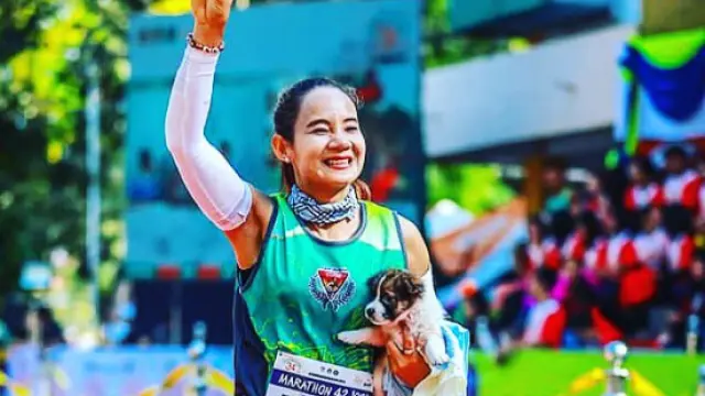 Khemjira Klongsanun con el cachorro en brazos corriendo la carrera en Tailandia.