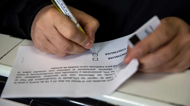 Un taxista escribe en una papeleta de la votación.
