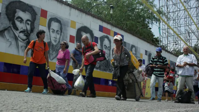 Varias personas cruzan la frontera entre Venezuela y Colombia.