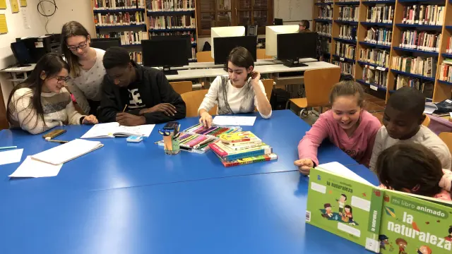 Niños de Fonz enseñan a leer y a escribir en la biblioteca a inmigrantes.