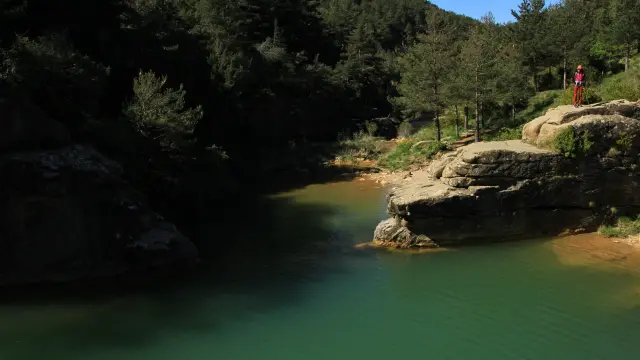 Las aguas verde esmeralda del pozo Pigalo, entre los cantiles de piedra y el bosque que lo rodean.
