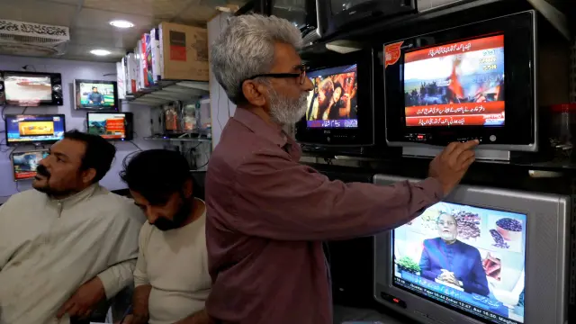 Un hombre mira la televisión que informa del derribo de los cazas indios.