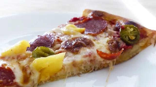 Sí, esto es una foto de trozo de pizza con piña.